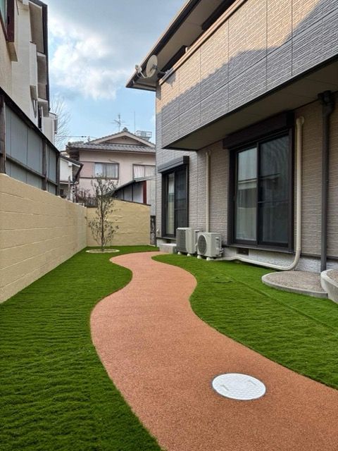 優雅な曲線のアプローチと人工芝で素敵なお庭に