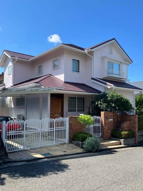 淡いピンクの外壁と赤みを帯びたブラウンの屋根の美しいコントラスト